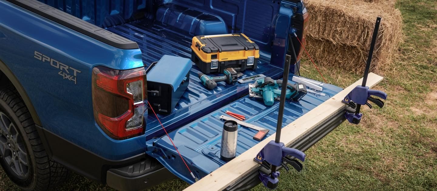 Caja de carga de una Ford Ranger azul con herramientas y un rack