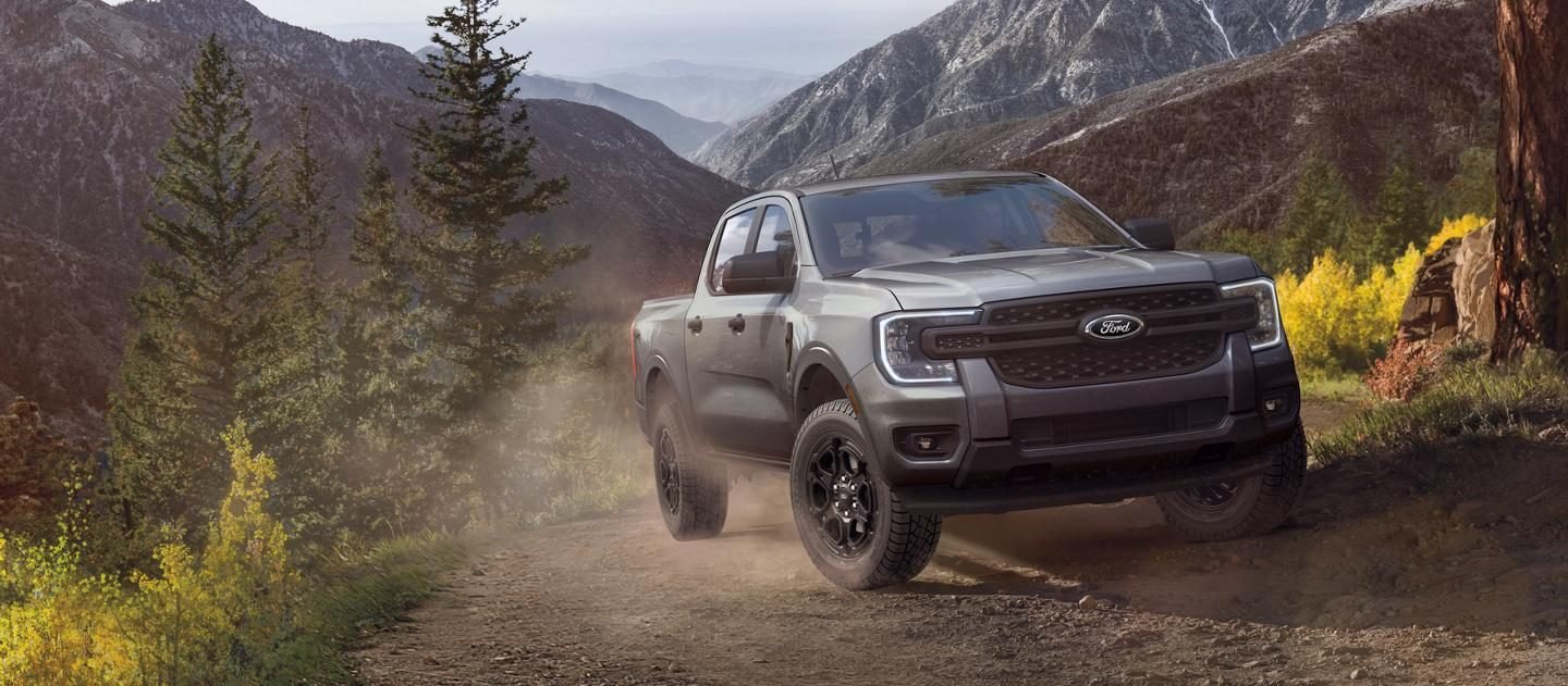 Ford Ranger negra bajando por un sendero de montaña entre árboles