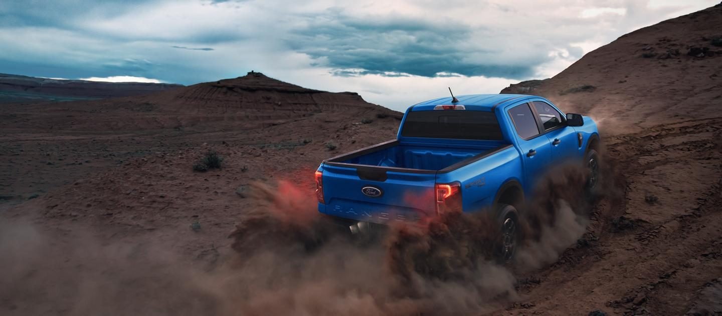 Ford Ranger azul levantando polvo en un terreno al atardecer