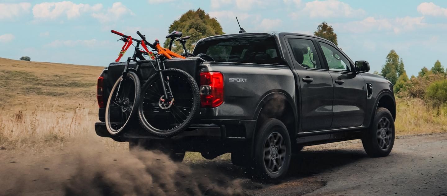Ford Ranger gris con bicicletas montadas en la caja en un camino rural