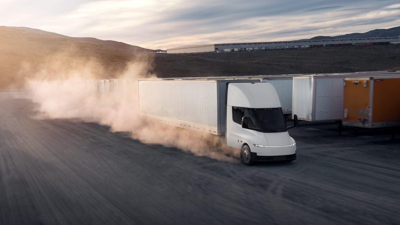 Tesla Semi levantando polvo en un patio logístico junto a remolques