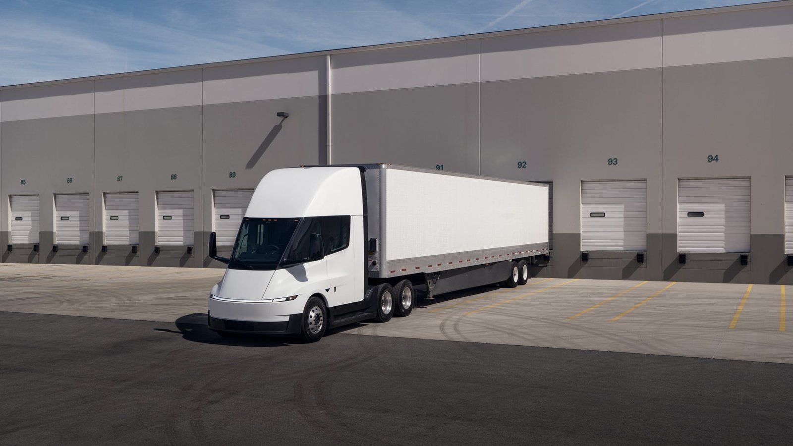 Tesla Semi con remolque blanco frente a un centro de distribución