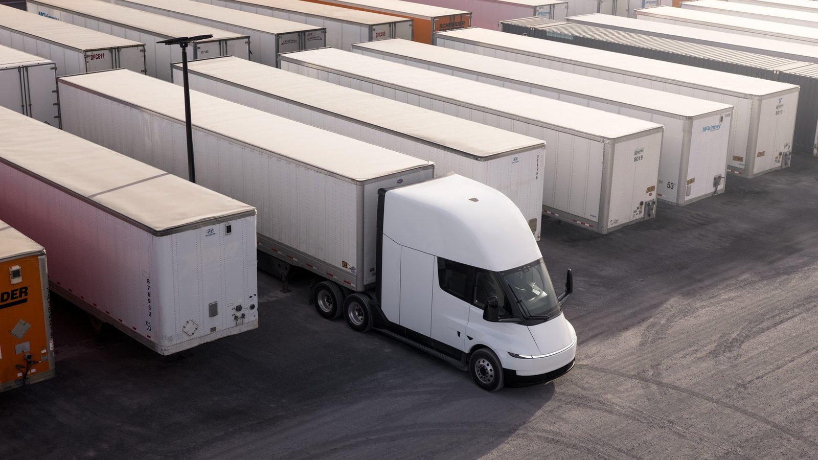 Vista aérea de un Tesla Semi maniobrando entre remolques en un patio logístico