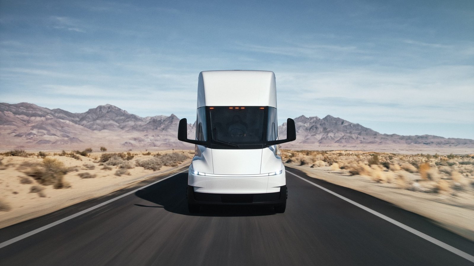 Vista frontal de un Tesla Semi en una carretera con montañas al fondo