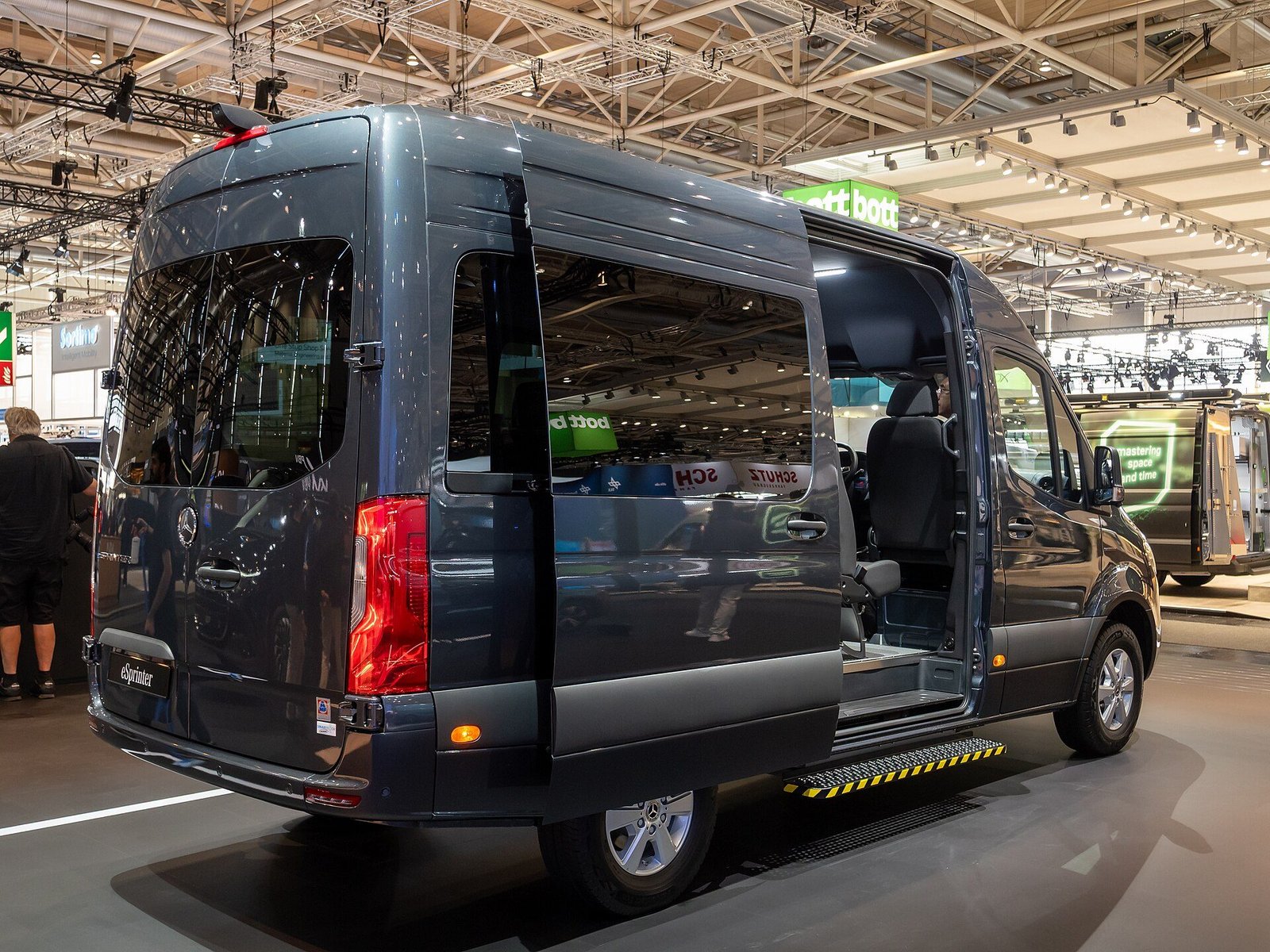 Mercedes-Benz eSprinter oscura con la puerta lateral abierta en un salón de exposición