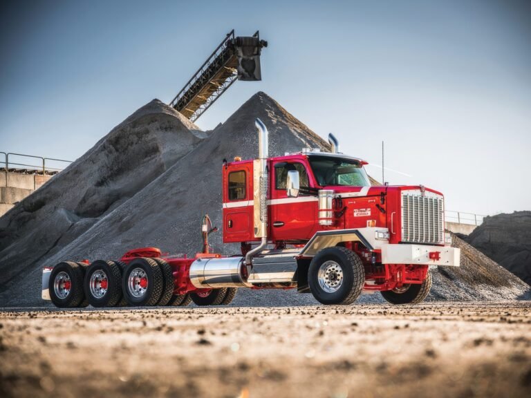 Kenworth C580 rojo de tres ejes traseros junto a una pila de grava en una cantera